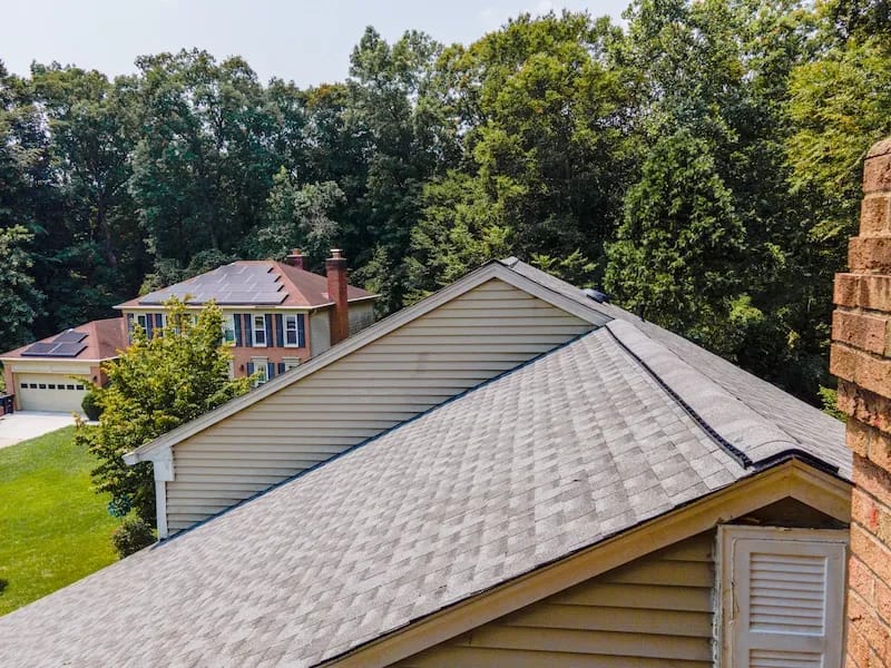 A detached shed with a green standing seam metal roof. 