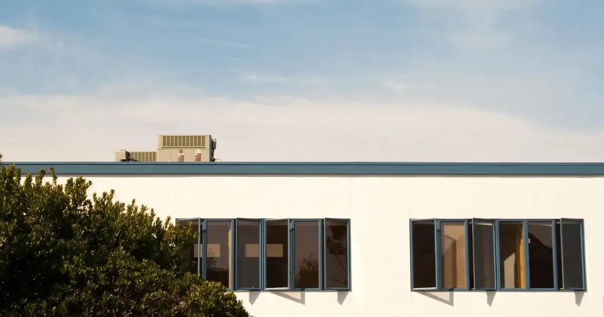 White modern home with a flat roof under a blue sky