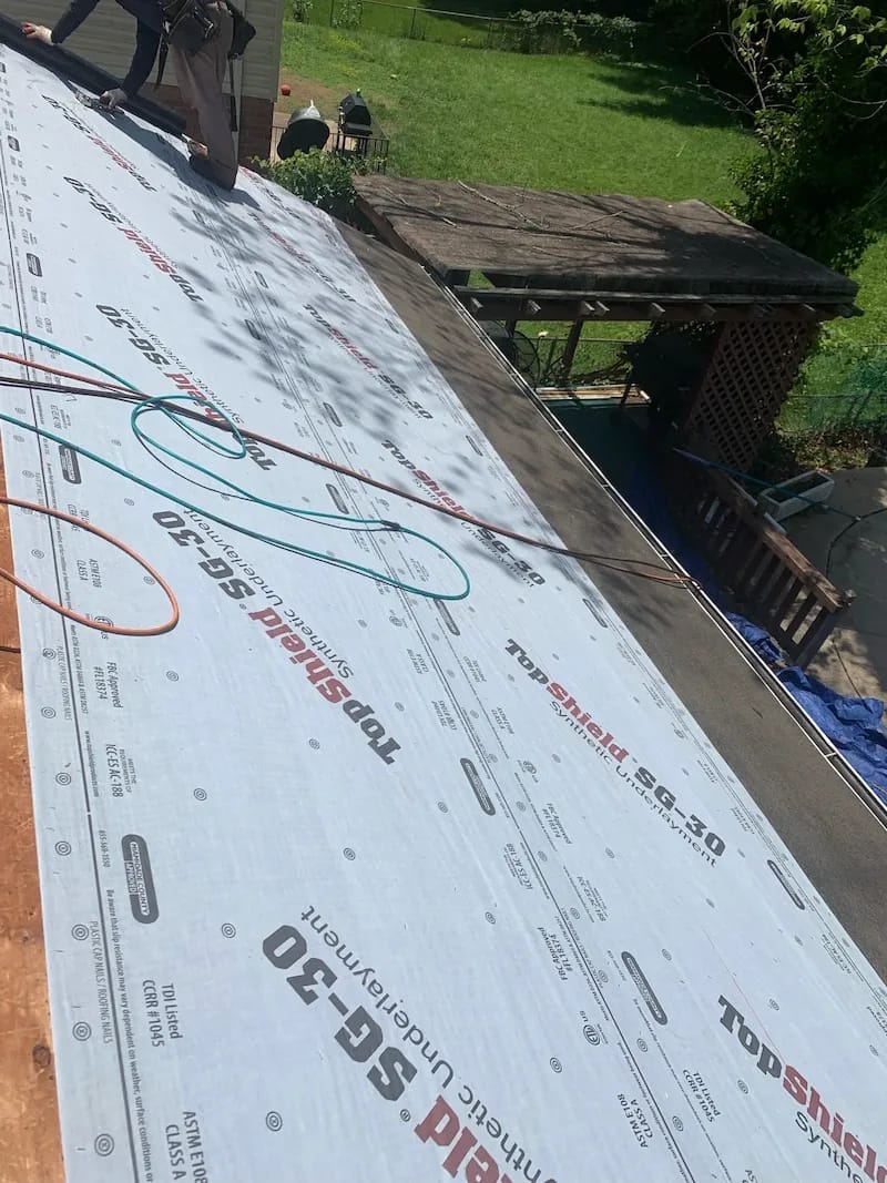 A detached shed with a green standing seam metal roof. 