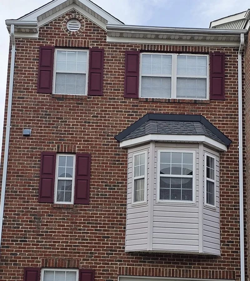 A detached shed with a green standing seam metal roof. 