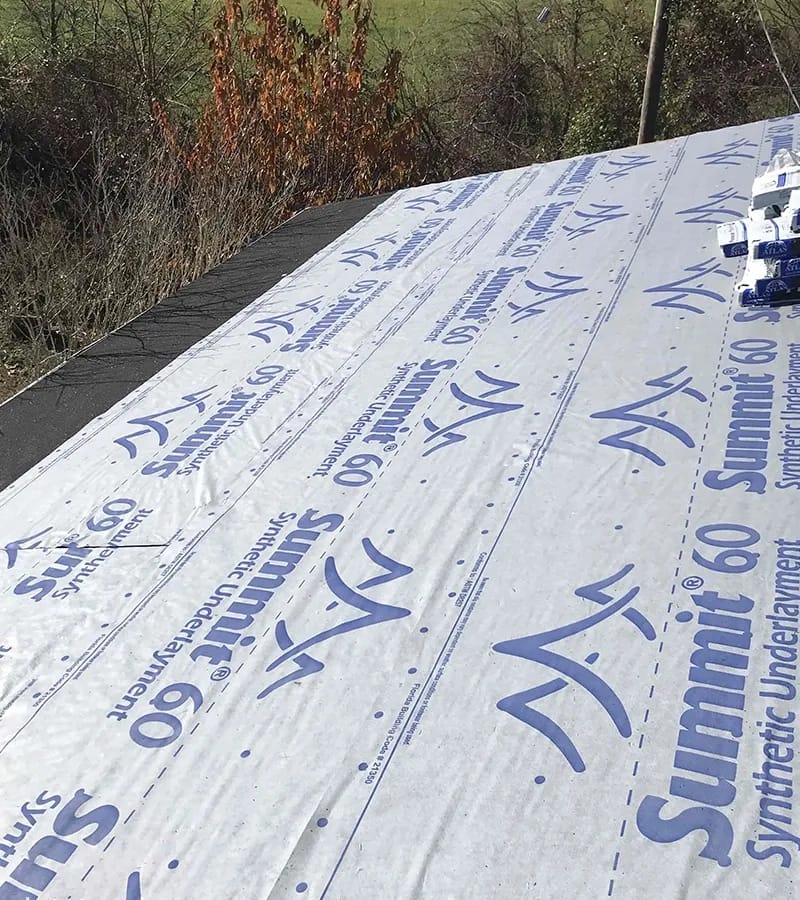 A detached shed with a green standing seam metal roof. 