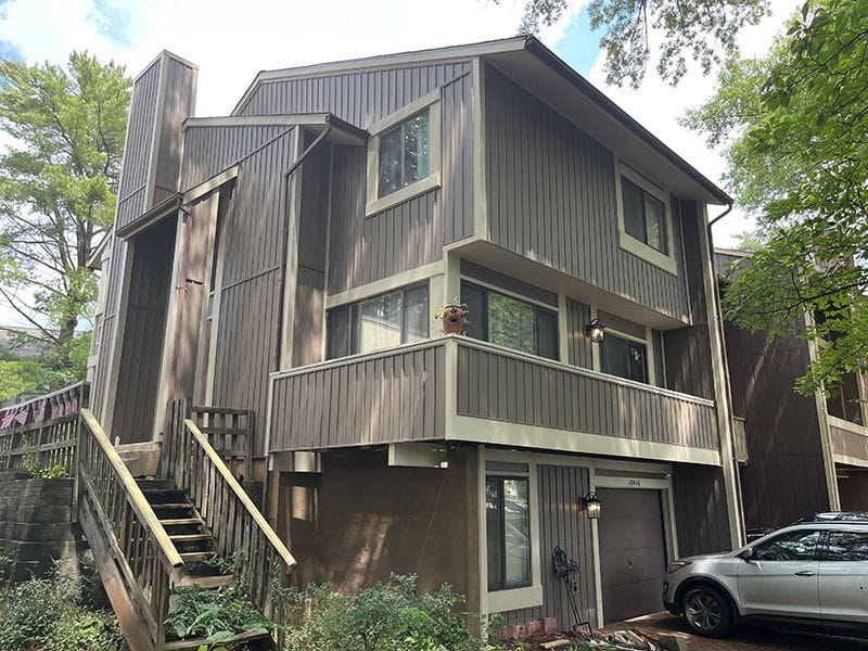 A detached shed with a green standing seam metal roof. 