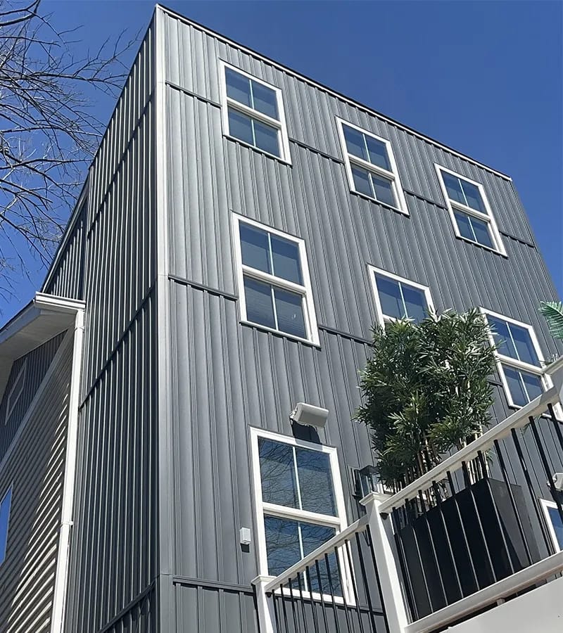A detached shed with a green standing seam metal roof. 