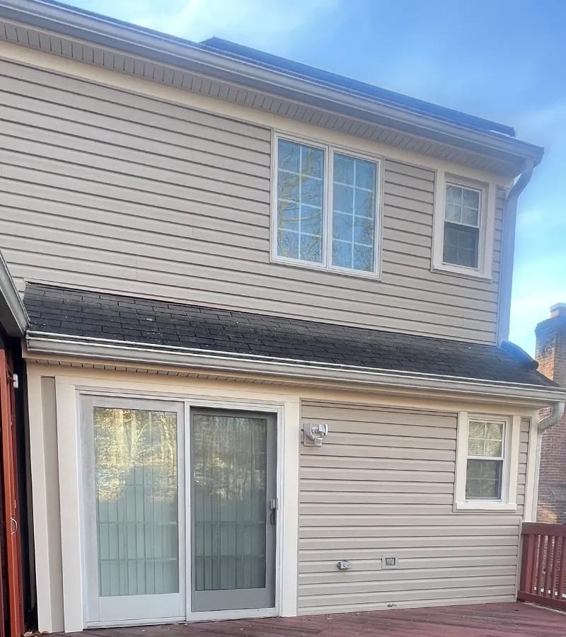A detached shed with a green standing seam metal roof. 