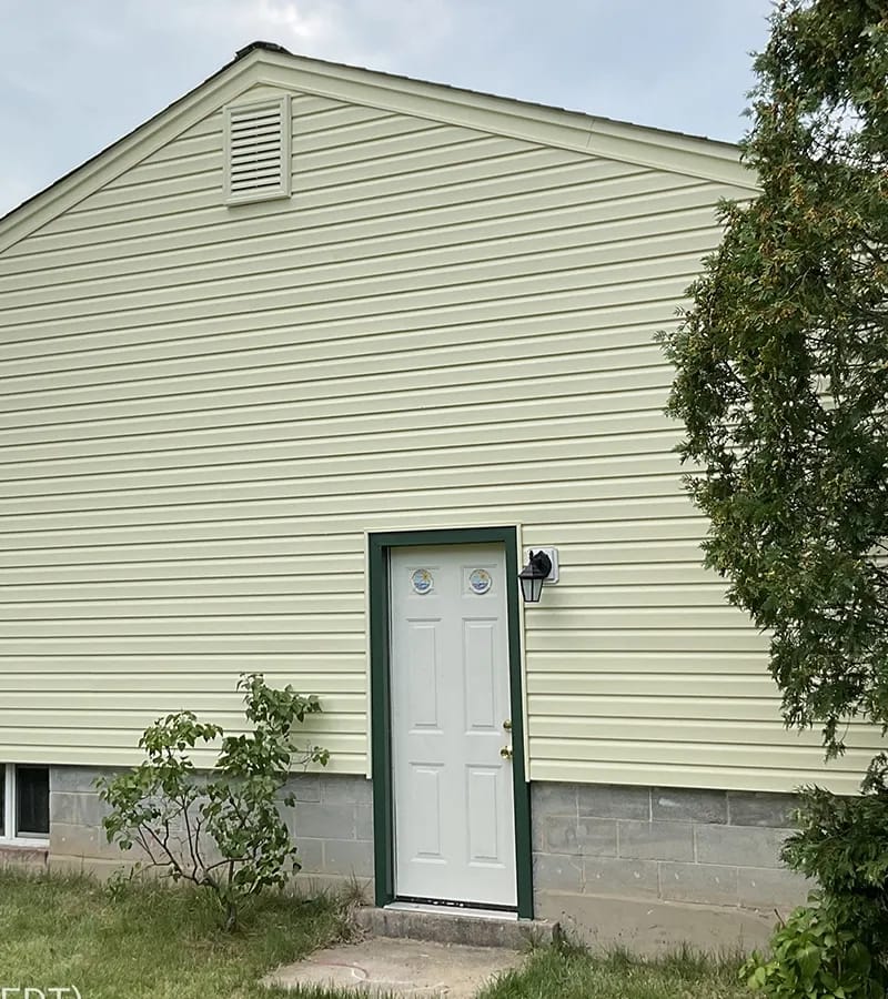 A detached shed with a green standing seam metal roof. 