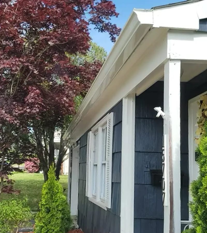 A detached shed with a green standing seam metal roof. 