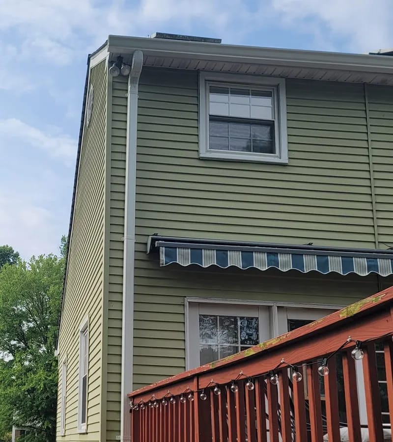 A detached shed with a green standing seam metal roof. 