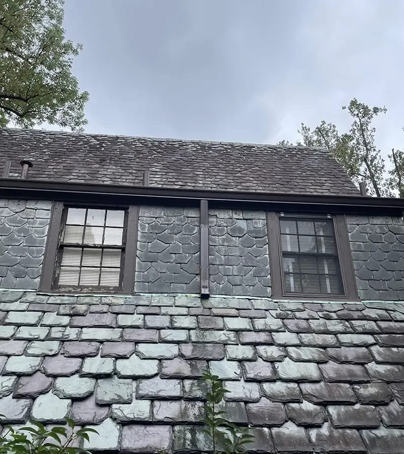 A detached shed with a green standing seam metal roof. 