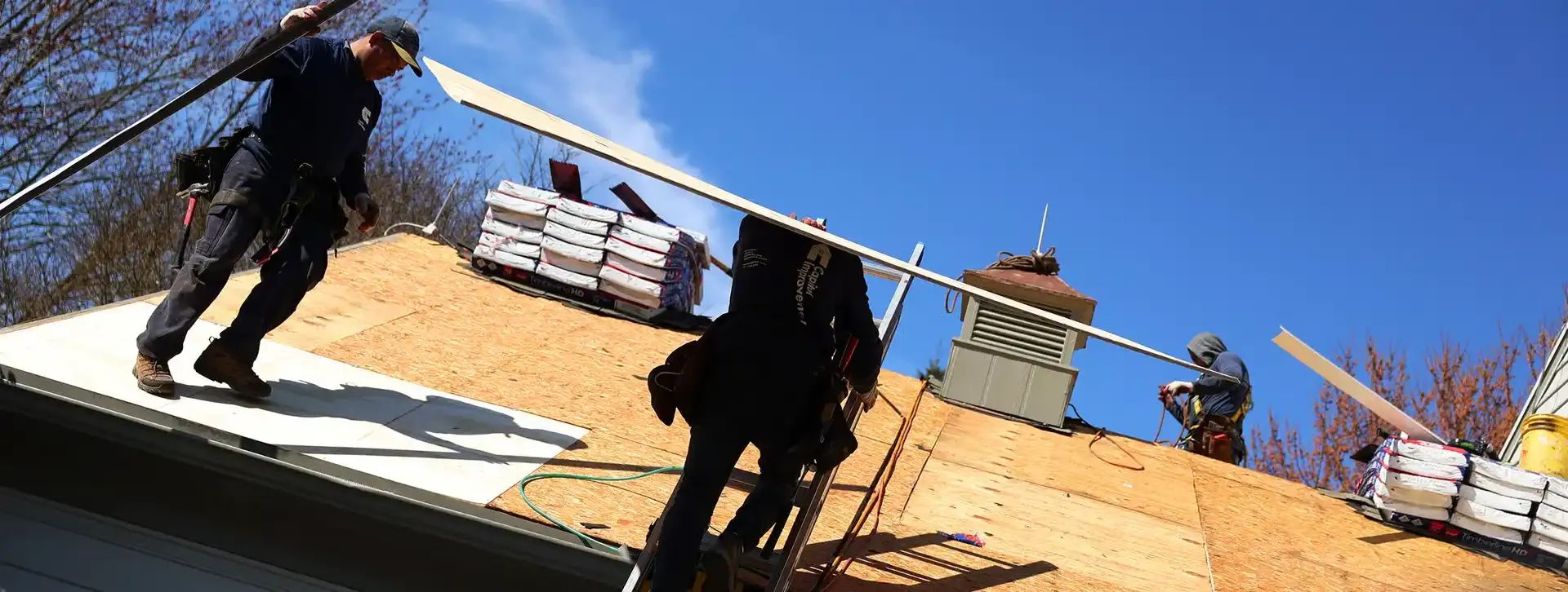 Crew carrying plywood to the roof. 