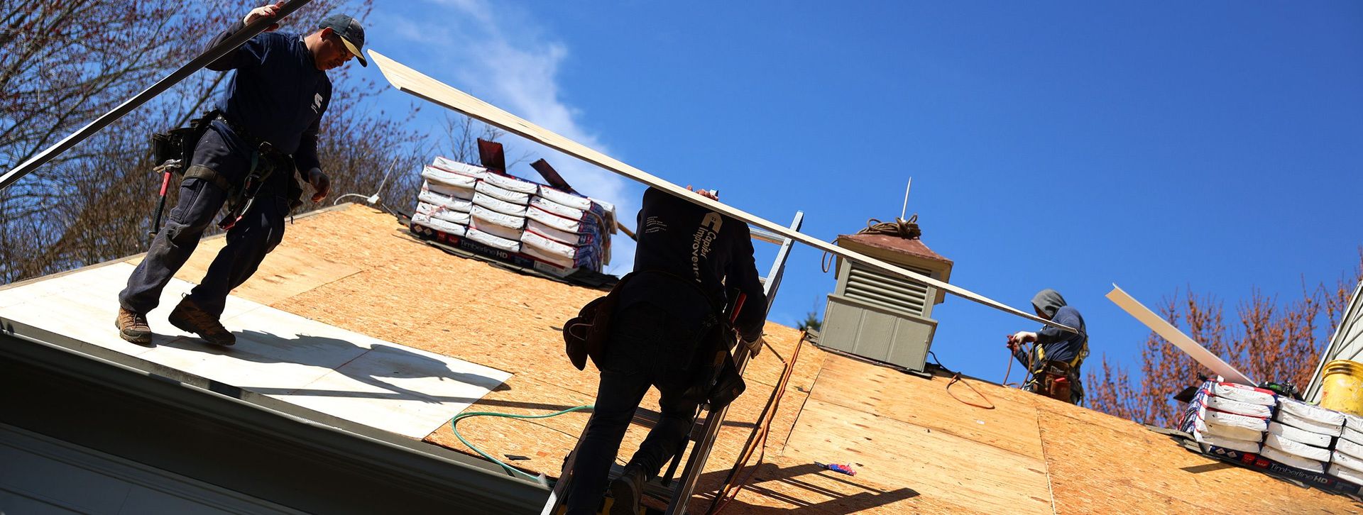 Crew carrying plywood to the roof. 