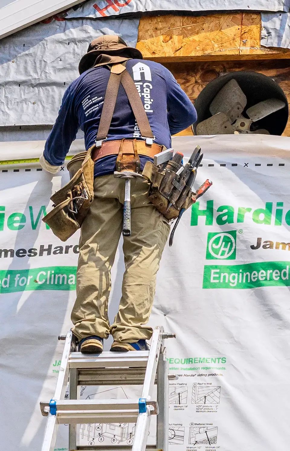Installing new siding on ladder.