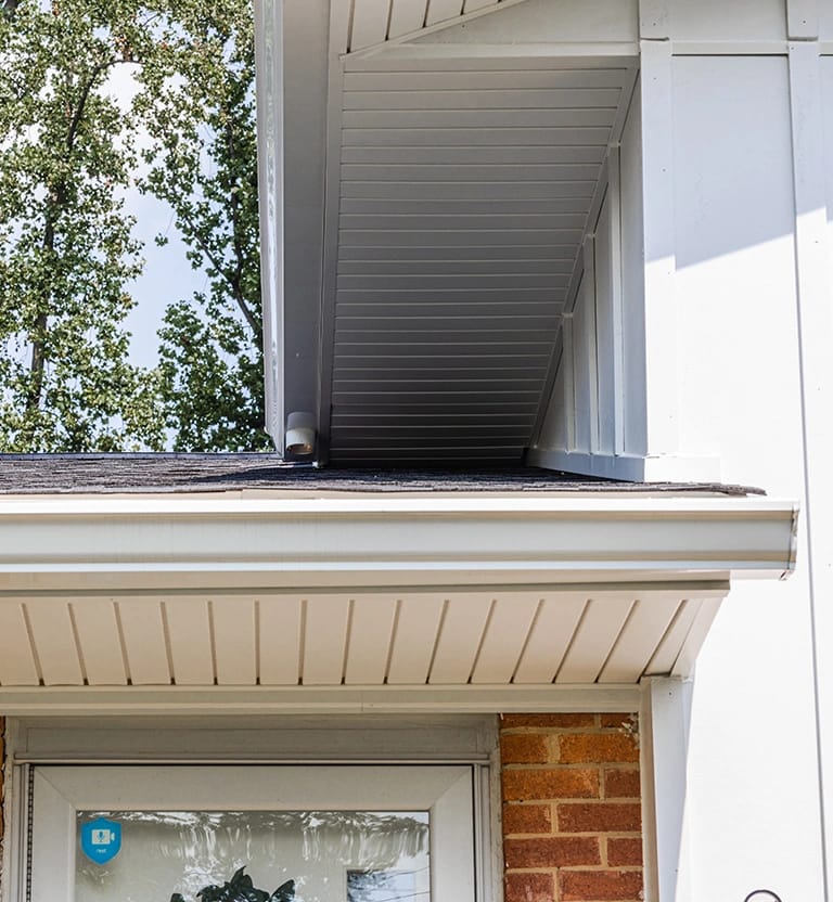 Seamless white gutters with hidden vent soffit.